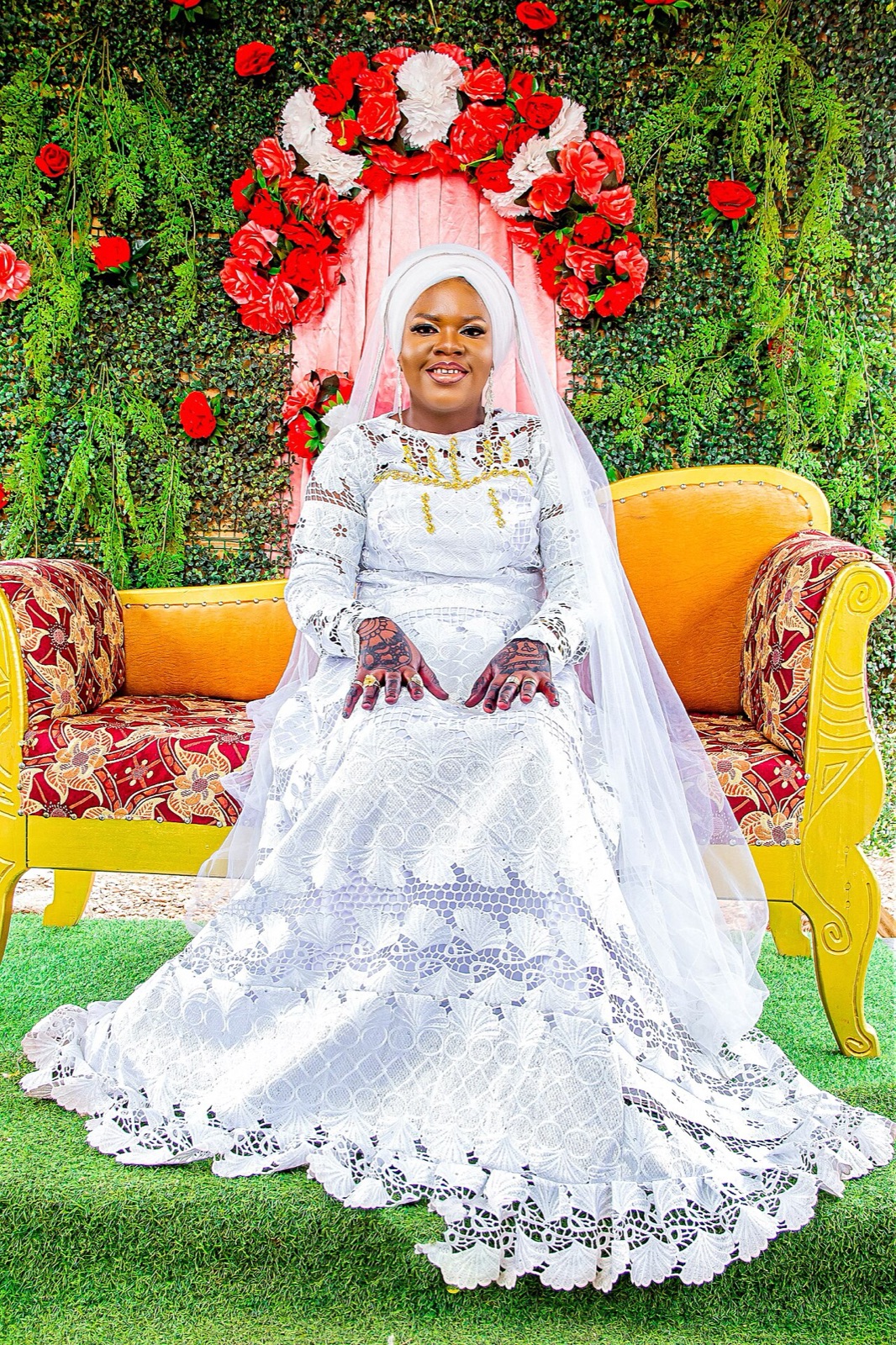 Bride in a white embroidered gown seated in a garden of roses