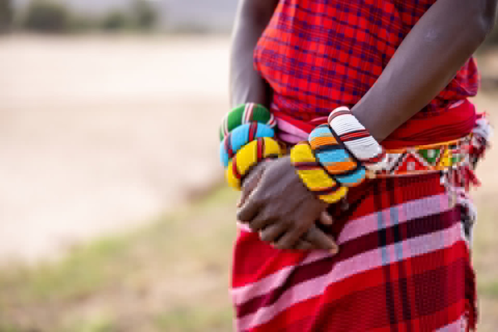 Close-up of beaded bracelets on hands against a red wrap